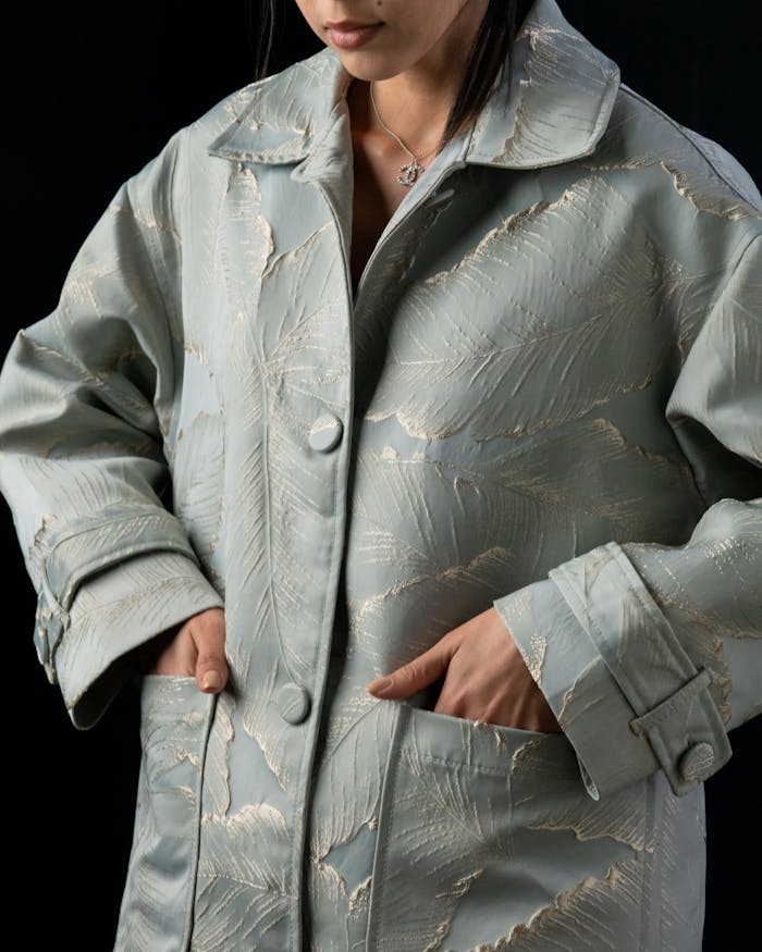 Woman wearing a sophisticated textured coat, hands in pockets.