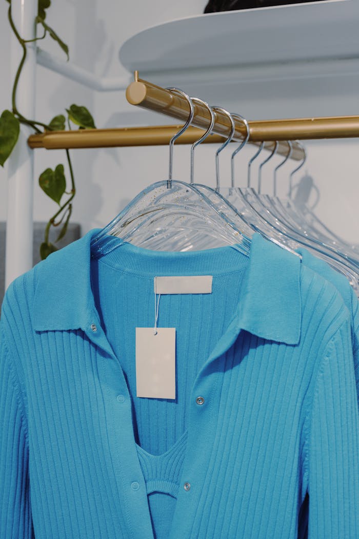 Stylish blue ribbed garments hang neatly on gold racks in a chic boutique setting.